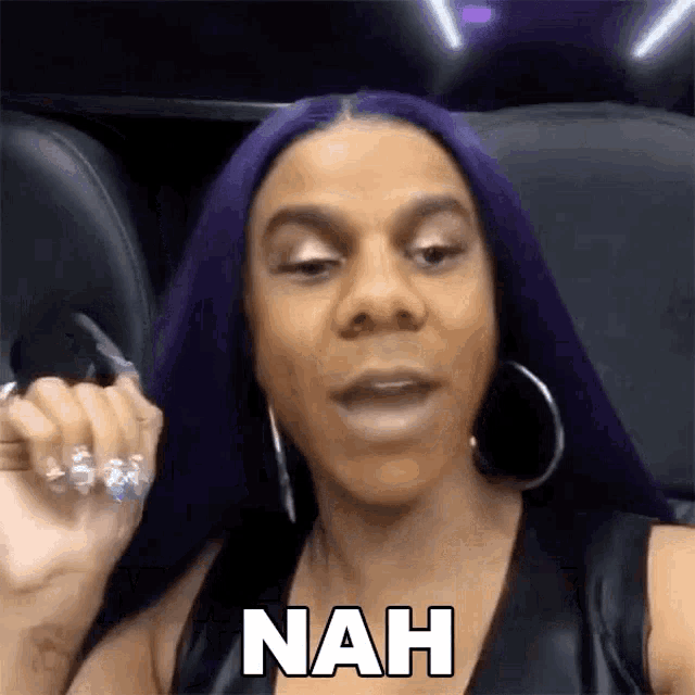 a woman with purple hair and hoop earrings is sitting in a car and says nah .