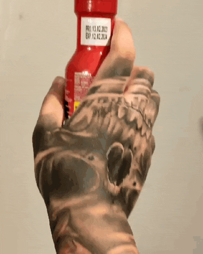 a person is holding a bottle of hot sauce with a chicken on it
