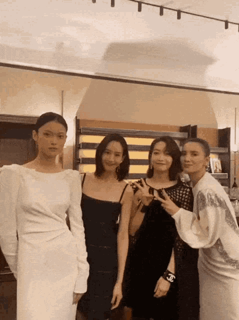 four women are posing for a picture and one has a chanel bracelet