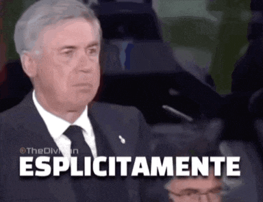 a man in a suit and tie is sitting in front of a sign that says esplicitamente