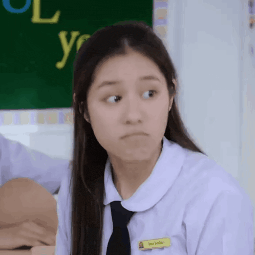 a girl in a school uniform and tie is making a face