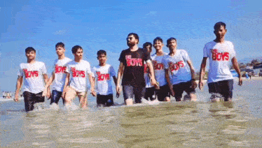 a group of boys wearing the boys t-shirts are walking in the water