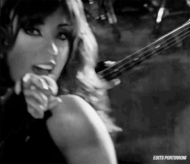 a black and white photo of a woman holding a violin with the words edits portirroni on the bottom