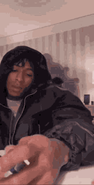 a man in a hooded jacket is holding a pen in his hand and writing on a piece of paper .