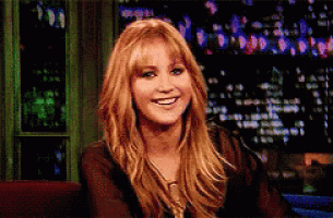 a woman with long blonde hair is smiling in front of a dark background