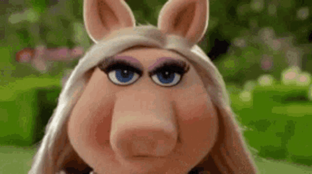 miss piggy from the muppet show is making a funny face and looking at the camera .