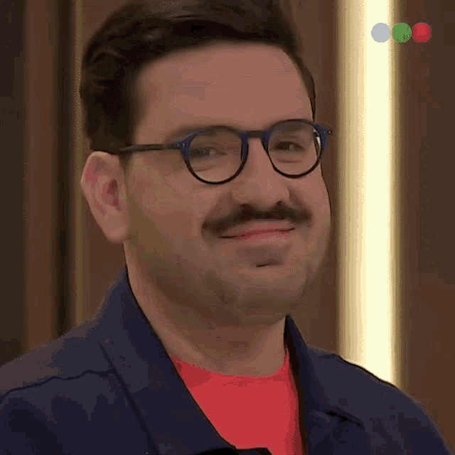 a man with glasses and a mustache is smiling for the camera