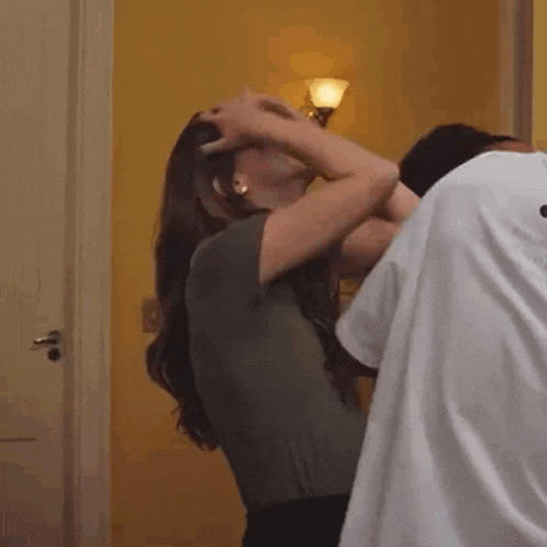 a man and a woman are kissing in a room . the woman is holding the man 's head .