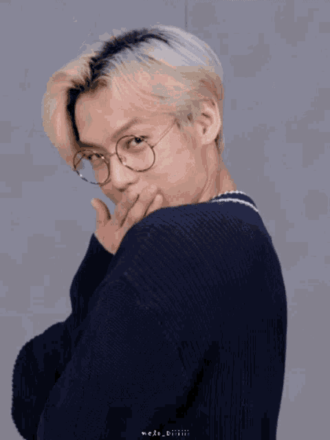 a young man wearing glasses and a sweater smiles