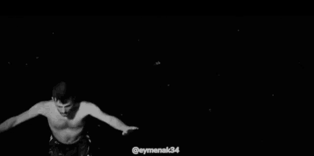 a black and white photo of a wave crashing on a beach at night