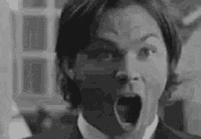 a man in a suit and tie is making a surprised face with his mouth open .
