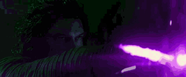a close up of a person in a hood with a purple light coming out of it .