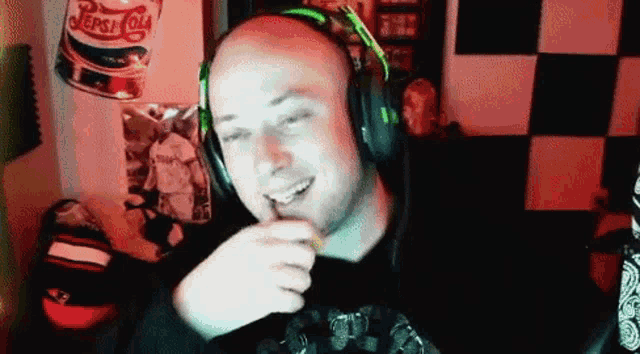 a bald man wearing headphones and a pepsi cola can behind him