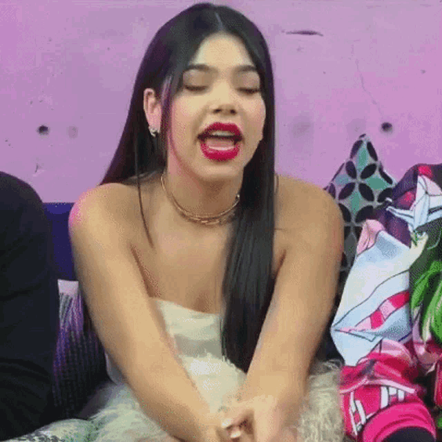 a woman with red lipstick is sitting on a couch with her mouth open
