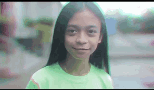 a young girl in a green shirt is smiling for the camera