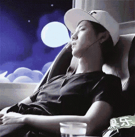 a man wearing a hat is sleeping in a chair with a glass of water next to him .