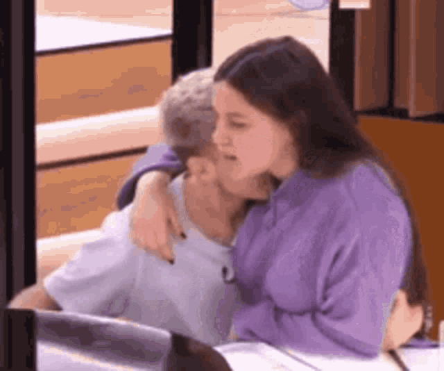 a woman is kissing a man on the cheek while they are sitting at a table .