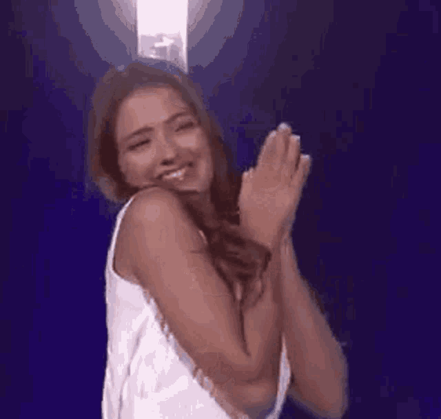 a close up of a woman laughing with her mouth open against a blue background .