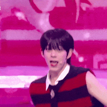 a young man is standing on a stage wearing a red and black striped shirt and tie .