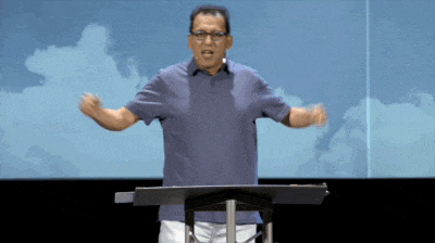 a man stands at a podium with his hands outstretched