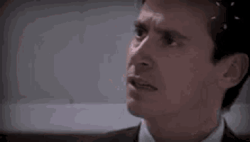 a man with a beard is looking at another man 's face in a blurry photo .