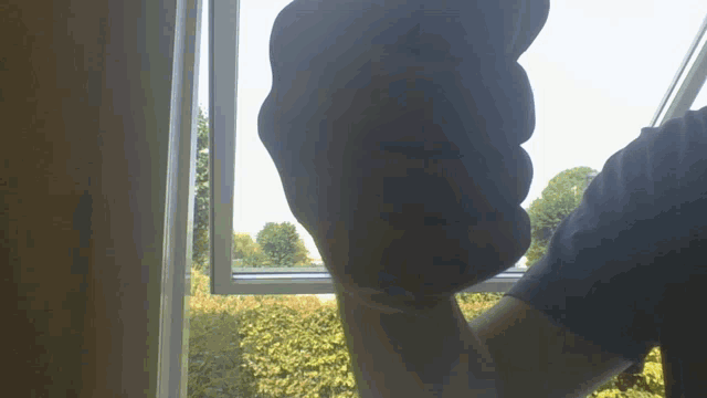a man 's fist is visible in front of a window