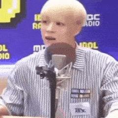 a man with a shaved head is talking into a microphone .