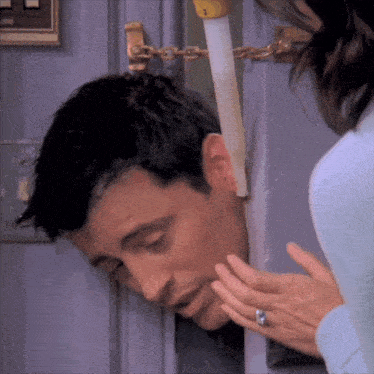 a man 's head is sticking out of a door while a woman looks on