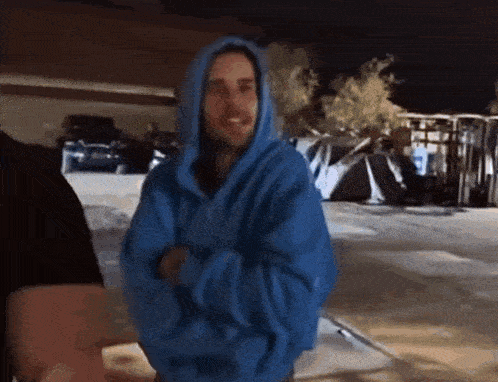 a man wearing a blue hoodie is standing in front of a building .
