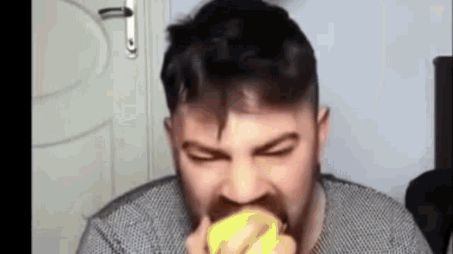 a man with a beard is eating a lemon .