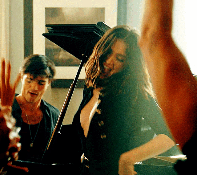 a woman is dancing in front of a piano while a man plays