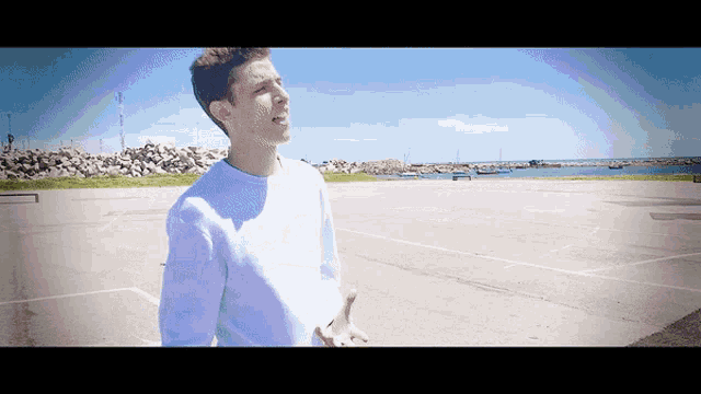 a young man stands in a parking lot with his hands outstretched