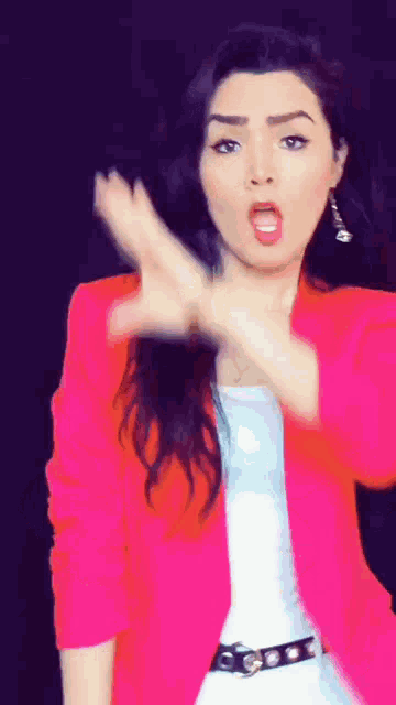 a woman wearing a pink jacket and white shirt is making a funny face