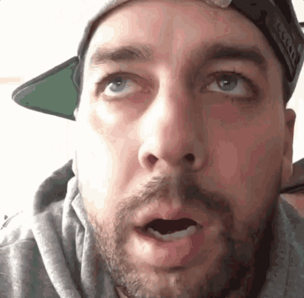 a man with a beard is wearing a hat and a hoodie