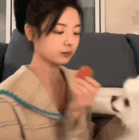 a woman sitting on a couch eating a strawberry