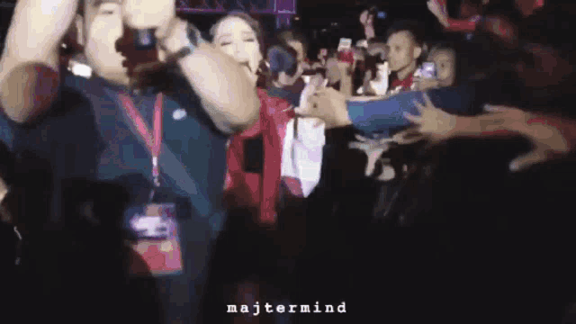 a woman singing into a microphone in front of a crowd with majtermind written on the bottom right
