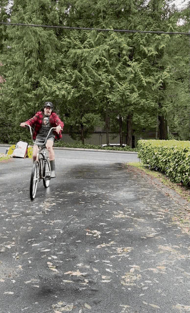 a man in a plaid shirt is riding a bicycle down a road