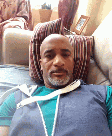a bald man with a beard is laying on a couch with a striped pillow
