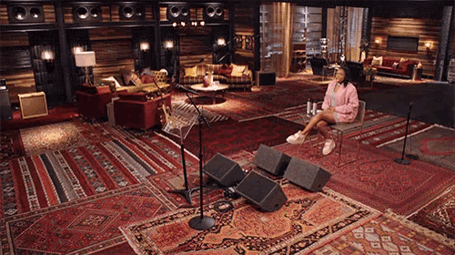 a woman sits in a chair in front of a microphone in a room