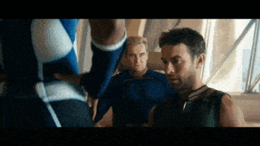 three men in superhero costumes are standing next to each other in a room