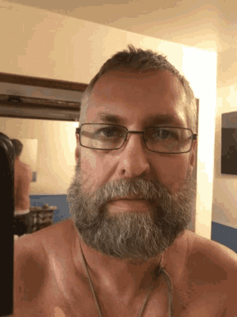 a man with a beard and glasses looks at the camera
