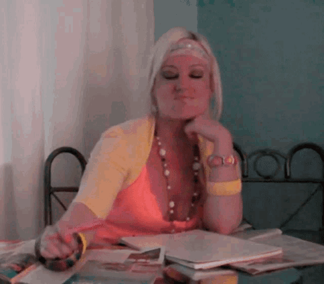 a woman wearing a yellow cardigan sits at a table with a notebook