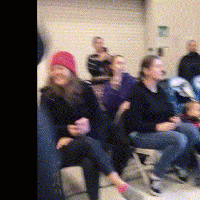 a group of people are sitting in chairs in a waiting room .