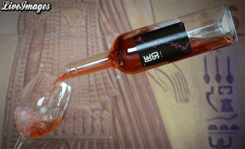 a bottle of rose wine is poured into a glass with live images in the corner