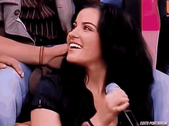 a woman is laughing while holding a microphone with edits portirroni written below her