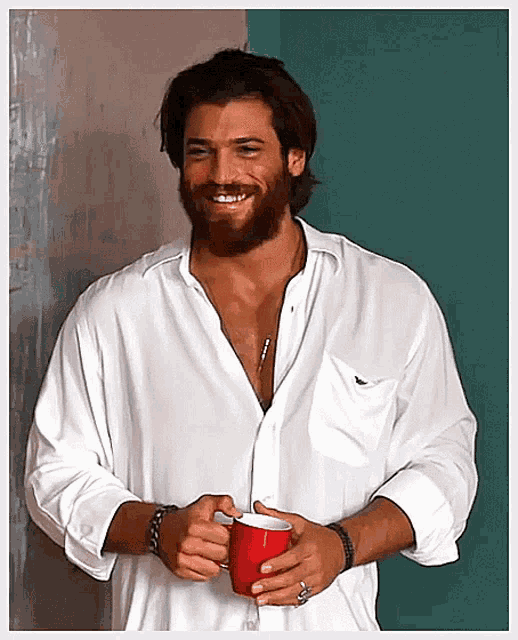 a man with a beard wearing a white shirt is holding a red cup