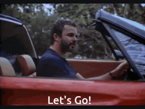 a man is driving a red car with the words let 's go on the screen