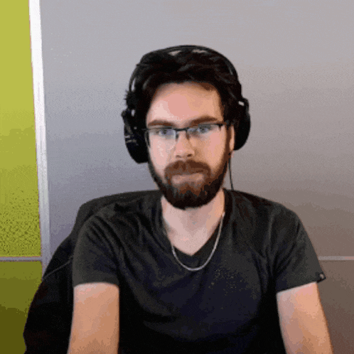 a man with a beard and glasses wearing headphones and a black shirt