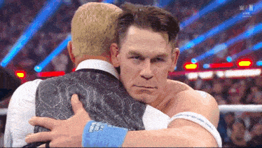 a man in a suit is hugging another man in front of a crowd .