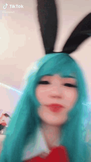 a woman with blue hair and bunny ears is wearing a blue wig and bunny ears .
